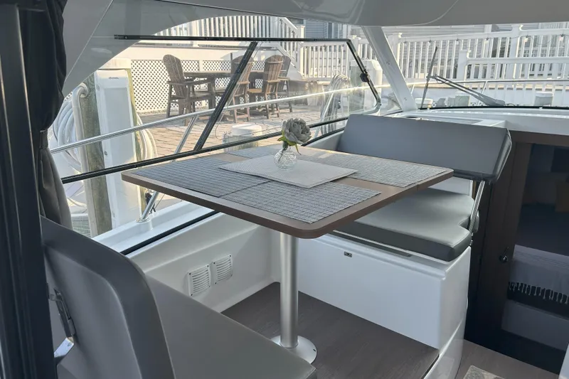  Yacht Photos Pics 2024 Beneteau Antares 9 interior with dining area, featuring a table and seating.