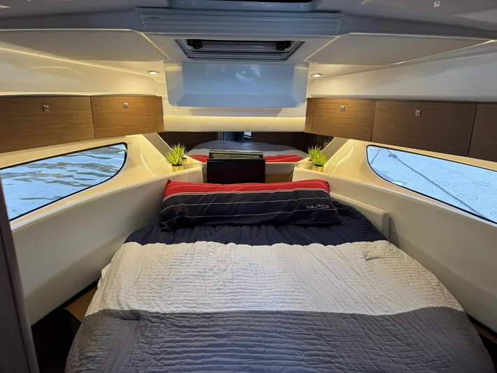  Yacht Photos Pics 2020 Jeanneau NC 1095 cabin interior with bed, windows, and wooden cabinets.