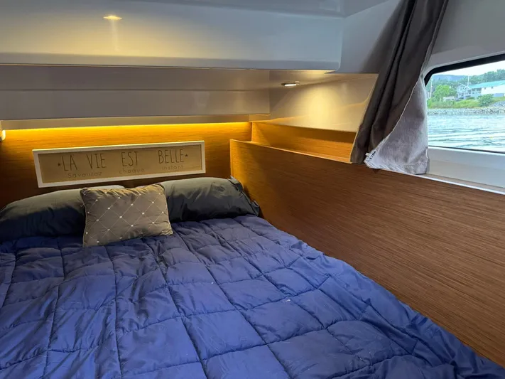  Yacht Photos Pics Cozy cabin interior of 2020 Jeanneau NC 1095 with blue bedding and wood accents.