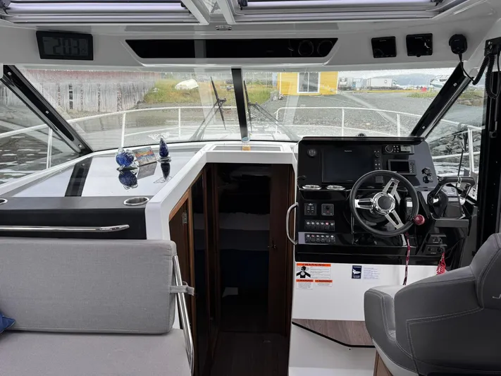 Yacht Photos Pics 2020 Jeanneau NC 1095 boat interior with steering wheel, dashboard, and seating area.