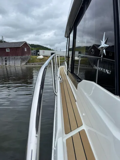  Yacht Photos Pics 2020 Jeanneau NC 1095 boat docked near rustic buildings on a cloudy day.