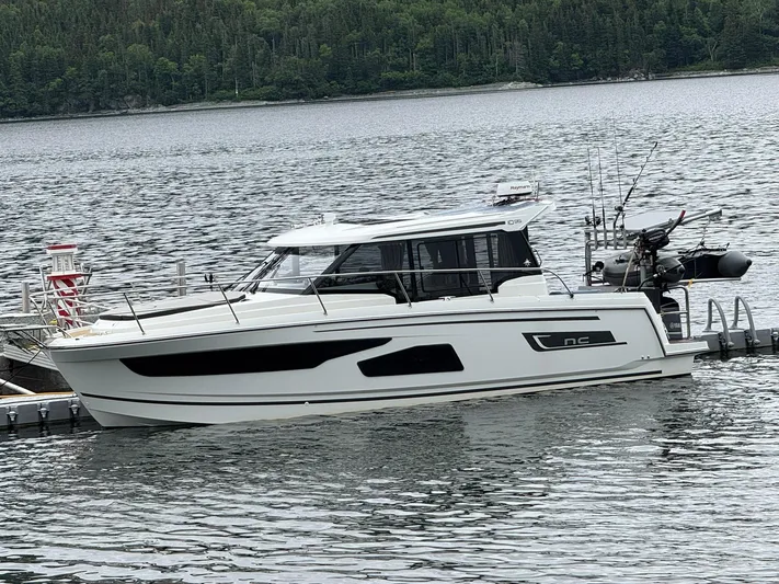 Yacht Photos Pics 2020 Jeanneau NC 1095 boat docked on a serene lake with forested background.