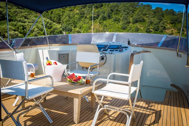Dali Yacht Photos Pics Luxurious yacht deck with seating, table, and refreshments, surrounded by lush greenery.