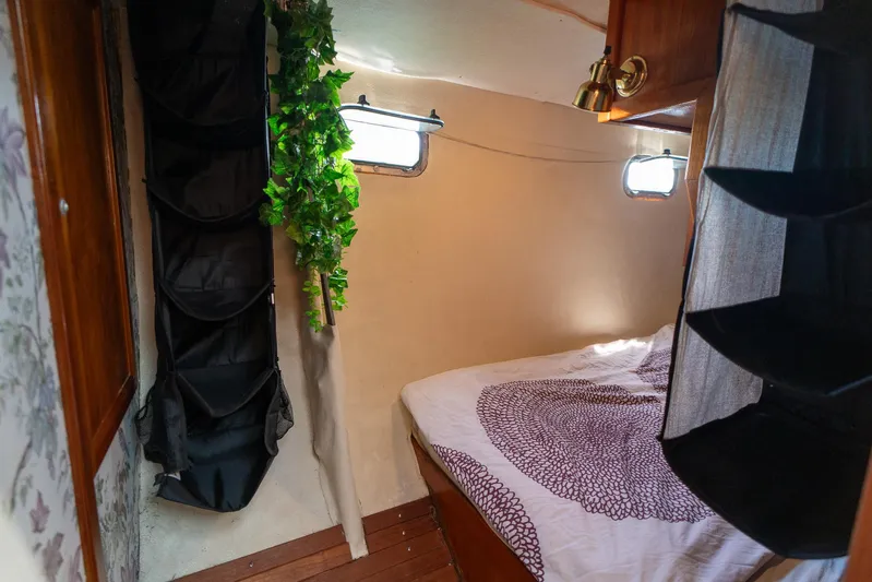 See The World Yacht Photos Pics Cozy boat cabin interior with bed, storage, and decorative greenery, Custom model 49, 1998.