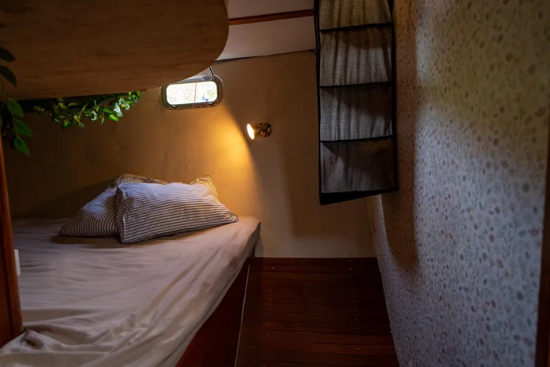 See The World Yacht Photos Pics Cozy cabin bedroom with striped pillows, soft lighting, and floral wallpaper.