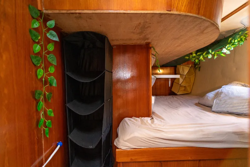 See The World Yacht Photos Pics Cozy wooden cabin interior with bed, storage, and decorative greenery, Custom model 49, 1998.