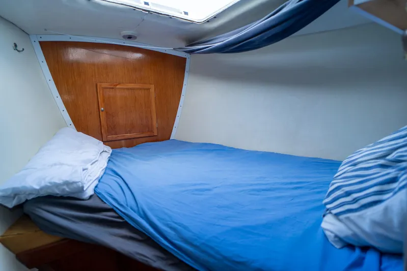 See The World Yacht Photos Pics Cozy boat cabin with blue bedding, wooden paneling, and a small storage compartment.