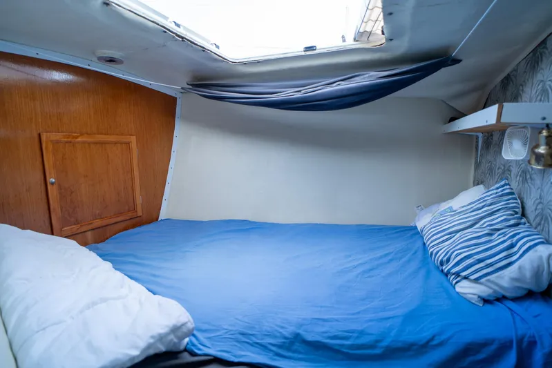 See The World Yacht Photos Pics Cozy boat cabin with blue bedding, wooden panel, and small window. Custom model 49, 1998.