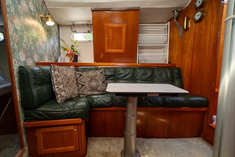 See The World Yacht Photos Pics Cozy boat interior with green leather seating, floral wallpaper, and decorative pillows, Custom 49 model, 1998.