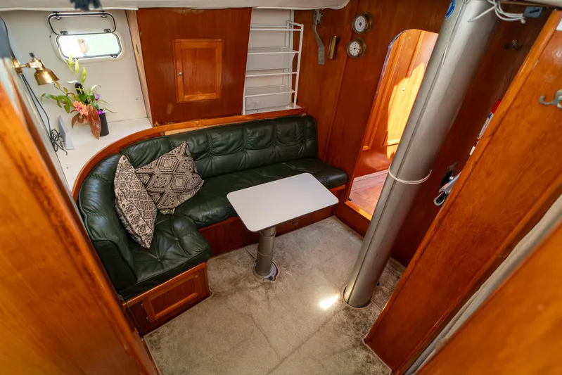 See The World Yacht Photos Pics Cozy boat interior with green leather seating, table, and wooden accents, Custom 49 model, 1998.
