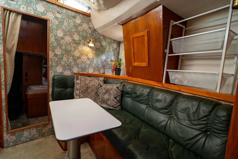 See The World Yacht Photos Pics Cozy boat interior with floral wallpaper, green leather seating, and a small table. Custom model 49, 1998.