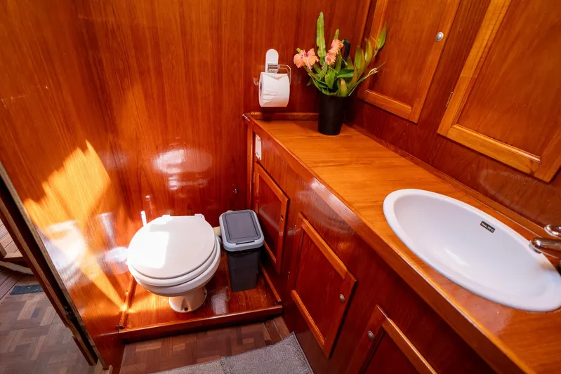 See The World Yacht Photos Pics Wood-paneled bathroom with toilet, sink, and decorative plant, Custom model 49, 1998.