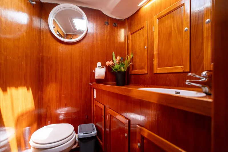 See The World Yacht Photos Pics Wood-paneled bathroom with round mirror, sink, and toilet in a 1998 Custom model 49.