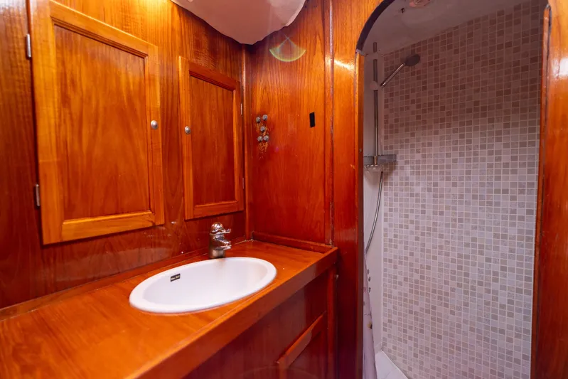 See The World Yacht Photos Pics Wood-paneled bathroom with sink and tiled shower in a 1998 Custom 49 model.