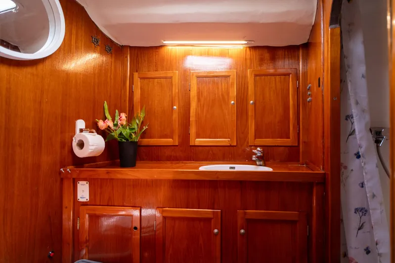 See The World Yacht Photos Pics Wood-paneled bathroom with sink, floral arrangement, and storage cabinets in a Custom 49 model, 1998.