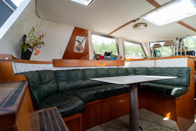 See The World Yacht Photos Pics Cozy boat interior with green leather seating, table, and decorative elements, Custom model 49, 1998.