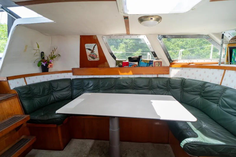 See The World Yacht Photos Pics Cozy boat interior with green leather seating, white table, and books on a Custom 49 model.