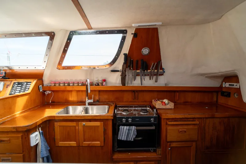 See The World Yacht Photos Pics Cozy boat kitchen with wooden cabinets, dual sink, stove, and knife rack, Custom 49 model, 1998.