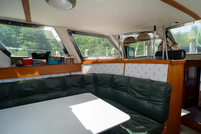 See The World Yacht Photos Pics Cozy boat interior with green seating, books, and a white table, Custom model 49, 1998.