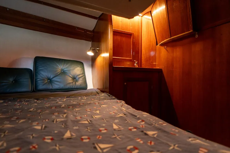 See The World Yacht Photos Pics Cozy cabin interior with nautical-themed bedding, wooden cabinetry, and soft lighting. Custom model 49, 1998.