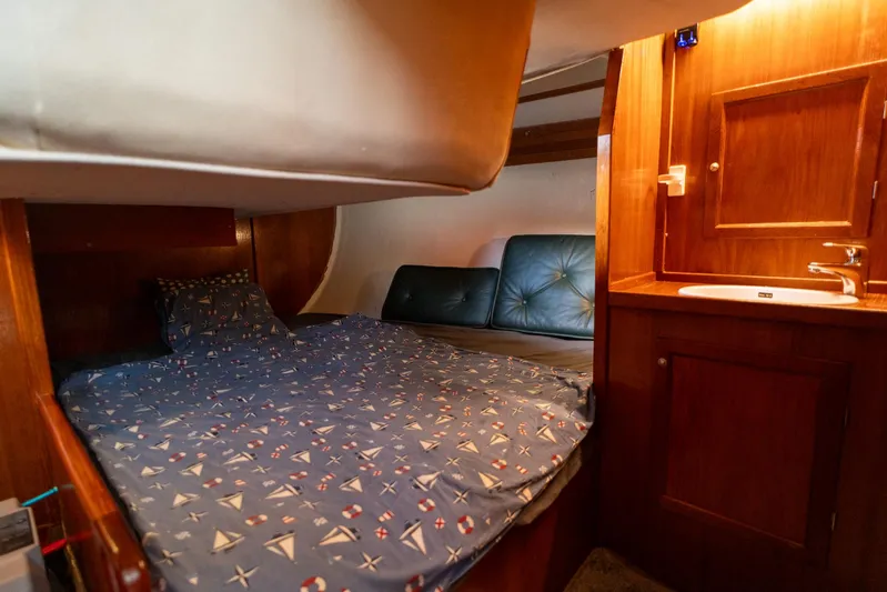 See The World Yacht Photos Pics Cozy cabin interior with nautical-themed bedding and wooden cabinetry, Custom 49, 1998 model.