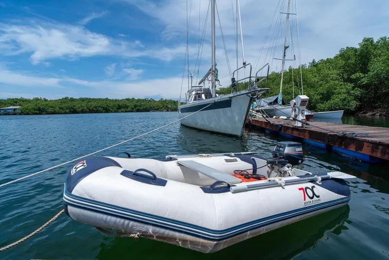 See The World Yacht Photos Pics Inflatable boat docked near sailboat on calm water, under a clear blue sky.