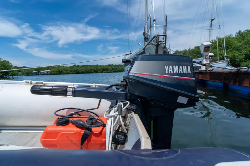 See The World Yacht Photos Pics Outboard motor on a boat with Yamaha branding, docked near lush greenery and blue sky.