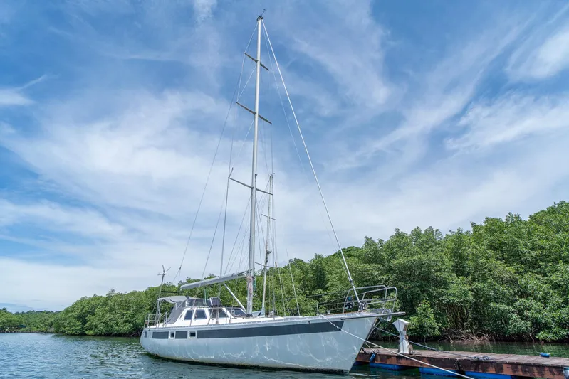 See The World Yacht Photos Pics Sailboat docked by lush greenery under a clear blue sky, Custom 49 model, 1998.