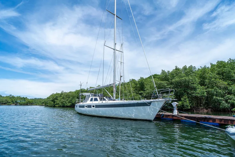 See The World Yacht Photos Pics Sailboat docked by lush mangroves under a clear blue sky, Custom 49 model, 1998.