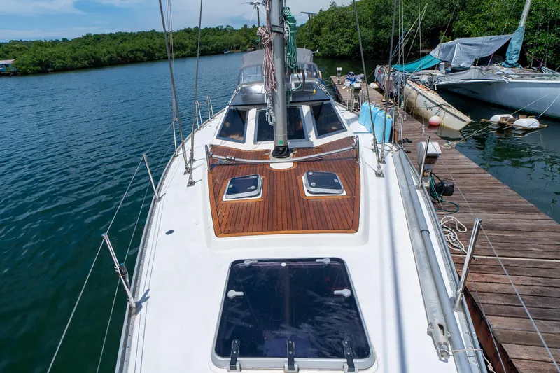 See The World Yacht Photos Pics Sailboat docked at marina, Custom 49 model, 1998, with wooden deck and lush surroundings.