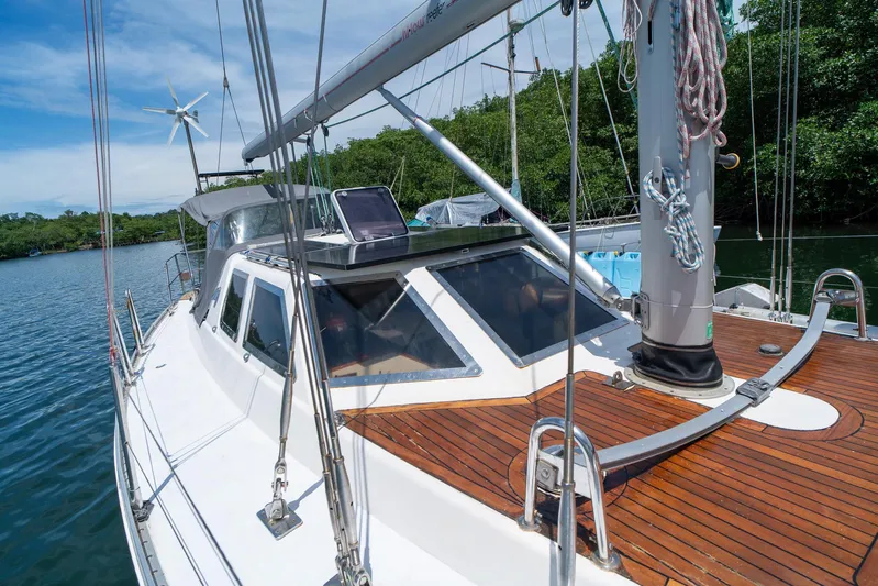 See The World Yacht Photos Pics Sailboat with wooden deck, Custom 49 model, 1998, docked near lush greenery.