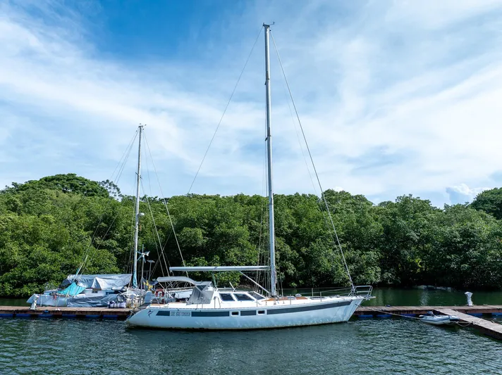 See The World Yacht Photos Pics Sailboat docked by lush greenery under a clear blue sky, Custom 49 model, 1998.