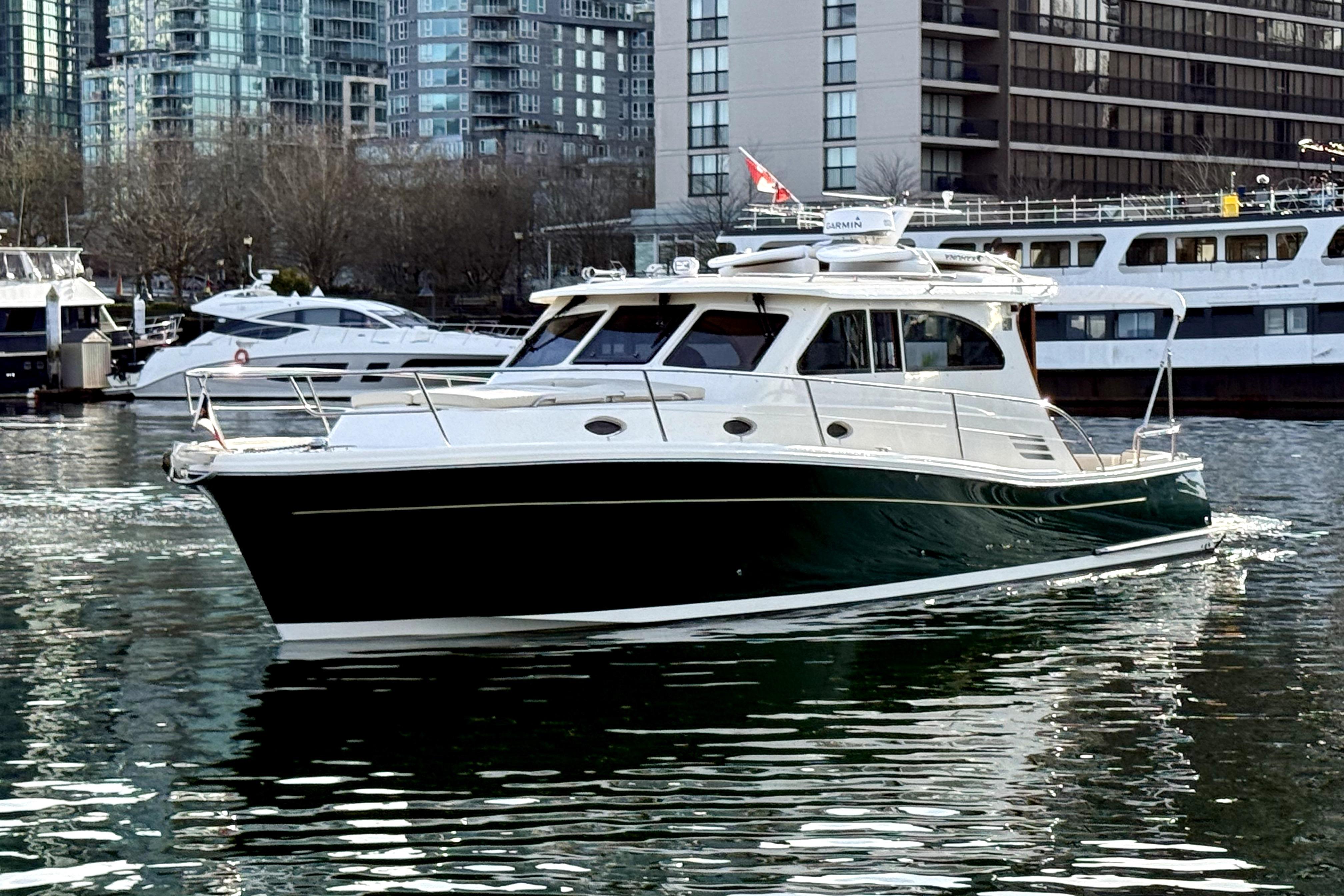 2012 Rivolta Coupe 4.5 yacht cruising in urban marina with modern buildings.