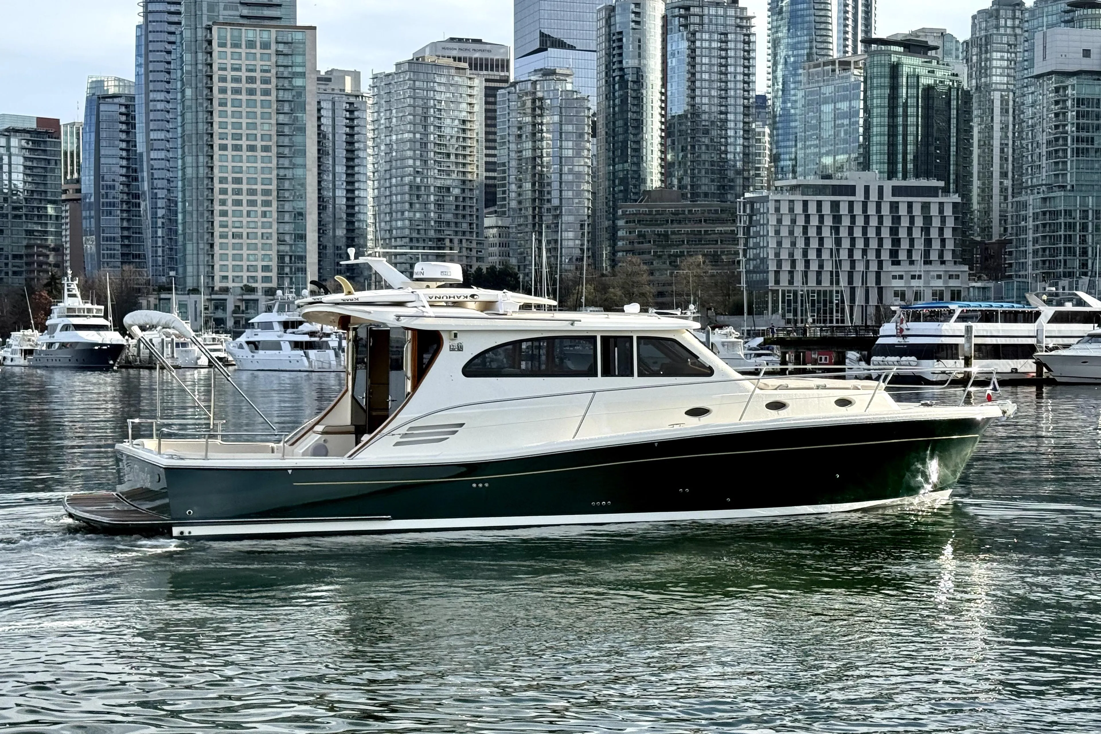 2012 Rivolta Coupe 4.5 yacht cruising in urban marina with skyscrapers in background.