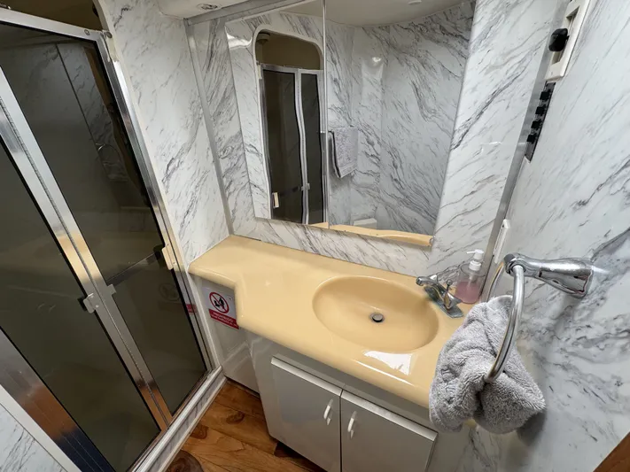 Calypso Yacht Photos Pics Bathroom interior of 1996 Viking 47 Convertible yacht with marble walls and beige sink.