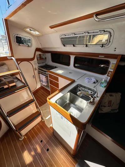 Ma Jolie Yacht Photos Pics Interior of a 1996 J Boats J/120 sailboat, featuring a compact kitchen and wooden flooring.