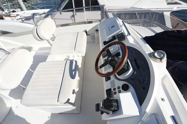 Coastal Pioneer Yacht Photos Pics Fairline Phantom 50 yacht helm, 2002 model, featuring dual white seats and a wooden steering wheel.