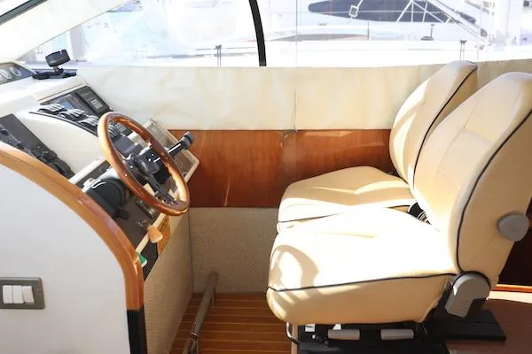 Coastal Pioneer Yacht Photos Pics Interior helm of 2002 Fairline Phantom 50 yacht with beige seats and wooden steering wheel.
