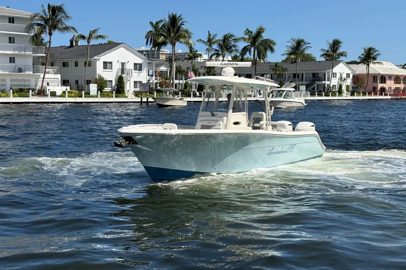 Joe Yacht Photos Pics 2018 Cobia 301 Center Console boat cruising on a sunny waterfront with palm trees.