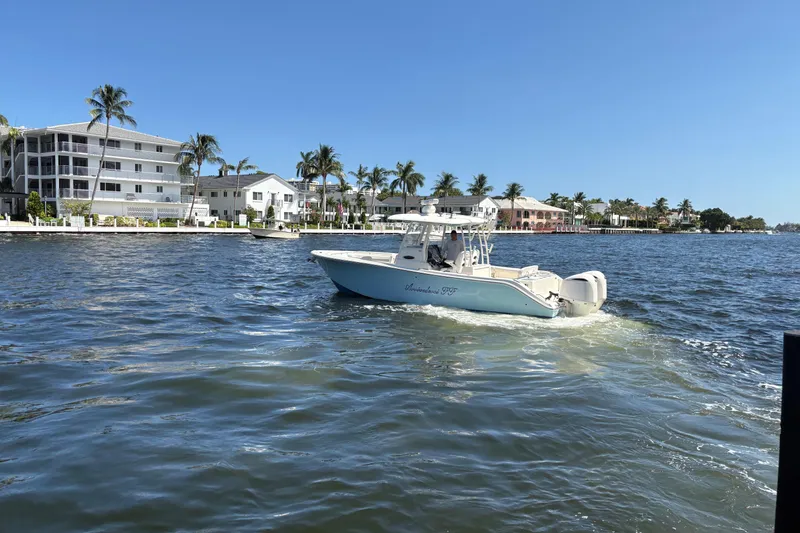 Joe Yacht Photos Pics 2018 Cobia 301 Center Console boat cruising on a sunny waterfront with palm trees.