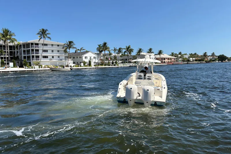 Joe Yacht Photos Pics 2018 Cobia 301 Center Console boat cruising near waterfront homes and palm trees.