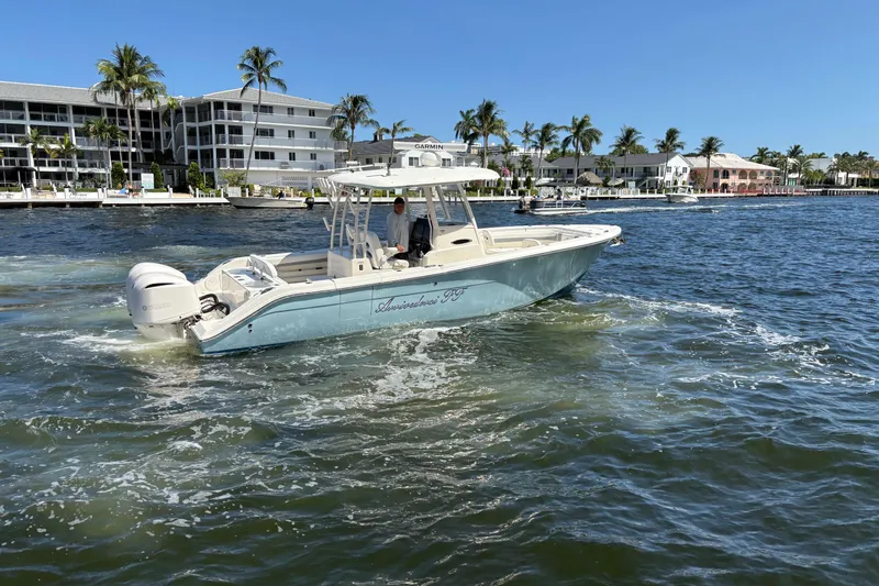 Joe Yacht Photos Pics 2018 Cobia 301 Center Console boat cruising near waterfront homes and palm trees.
