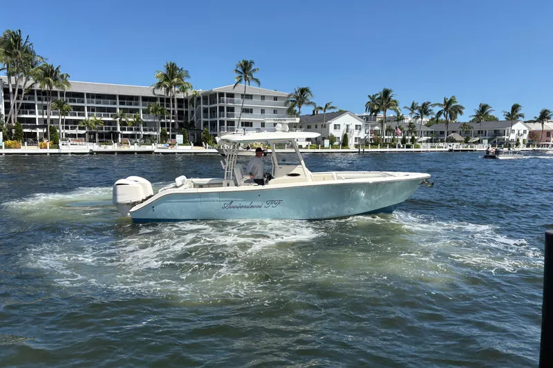 Joe Yacht Photos Pics 2018 Cobia 301 Center Console boat cruising on a sunny waterfront with palm trees.