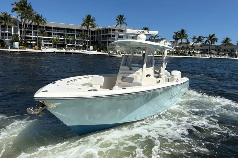 Joe Yacht Photos Pics 2018 Cobia 301 Center Console boat cruising on water near waterfront buildings.