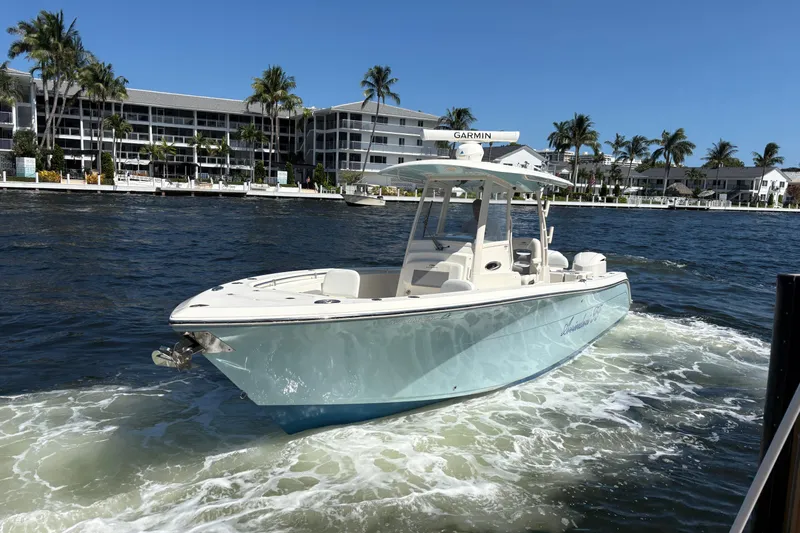 Joe Yacht Photos Pics 2018 Cobia 301 Center Console boat cruising on a sunny waterfront with palm trees.
