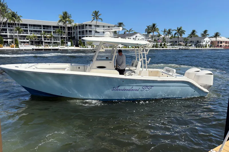 Joe Yacht Photos Pics 2018 Cobia 301 Center Console boat on water near palm trees and buildings.