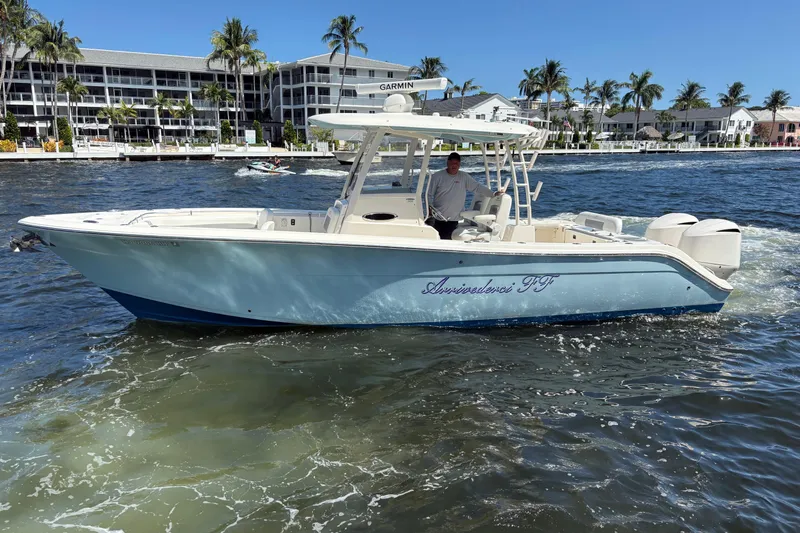 Joe Yacht Photos Pics 2018 Cobia 301 Center Console boat cruising on a sunny day near waterfront buildings.