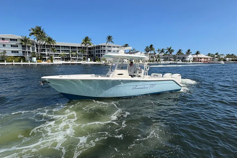 Joe Yacht Photos Pics 2018 Cobia 301 Center Console boat cruising near waterfront buildings and palm trees.