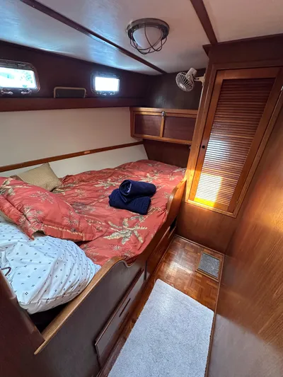 Unexpected Pleasure Yacht Photos Pics Cozy cabin interior of 1985 Nautical Development 56 yacht with wooden furnishings and bedding.
