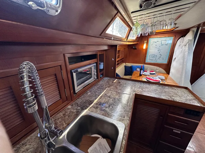 Unexpected Pleasure Yacht Photos Pics Interior of 1985 Nautical Development 56 yacht with kitchen and dining area.